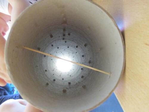 Regenmacher aus einem Papprohr, Schaschlikspießen und Erbsen.